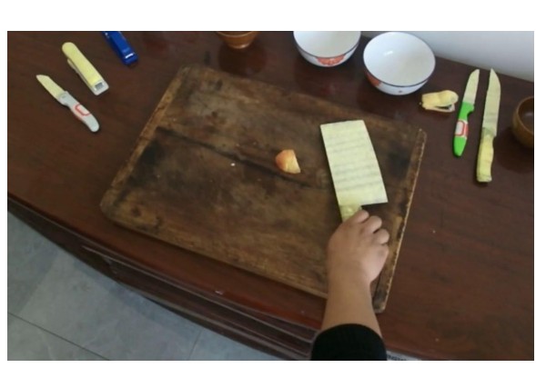 Input photo: a hand holding a knife over a cutting board.