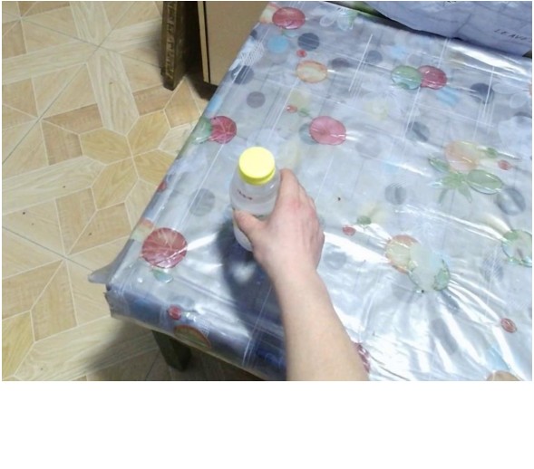 Input photo: a hand holding a bottle on a table.